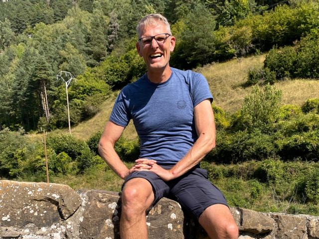 Stefan Höne sitzt auf eine Steinmauer in Spanien
